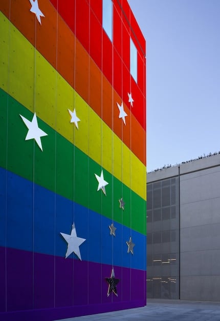 A close-up of hands holding a rainbow flag in front of a government building in China, symbolizing the struggle for LGBTQ+ rights and legal recognition in the country.